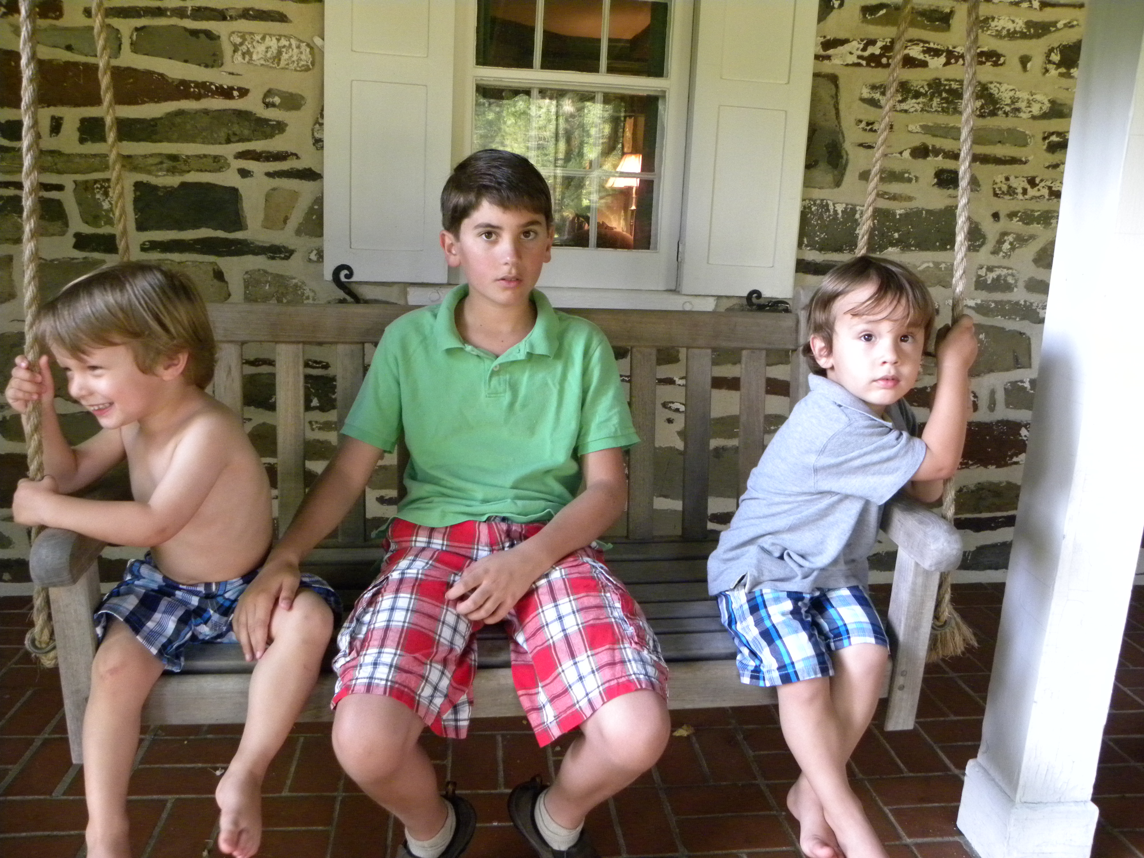 Errol seated on a swing seat with his brothers, Mac and Piers