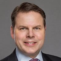 Neil Johnson - a man wearing a suit and tie smiles at the camera