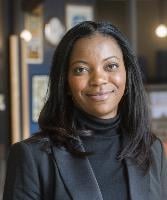 Olaide Oboh - a woman wearing a black roll neck and suit jacket smiles at the camera