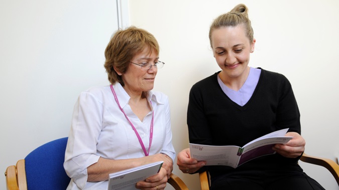 Patient and doctor sat next to one another reviewing treatment document