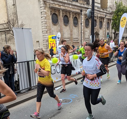 A woman participating in a marathon, arms elevated in excitement as she sprints towards the finish