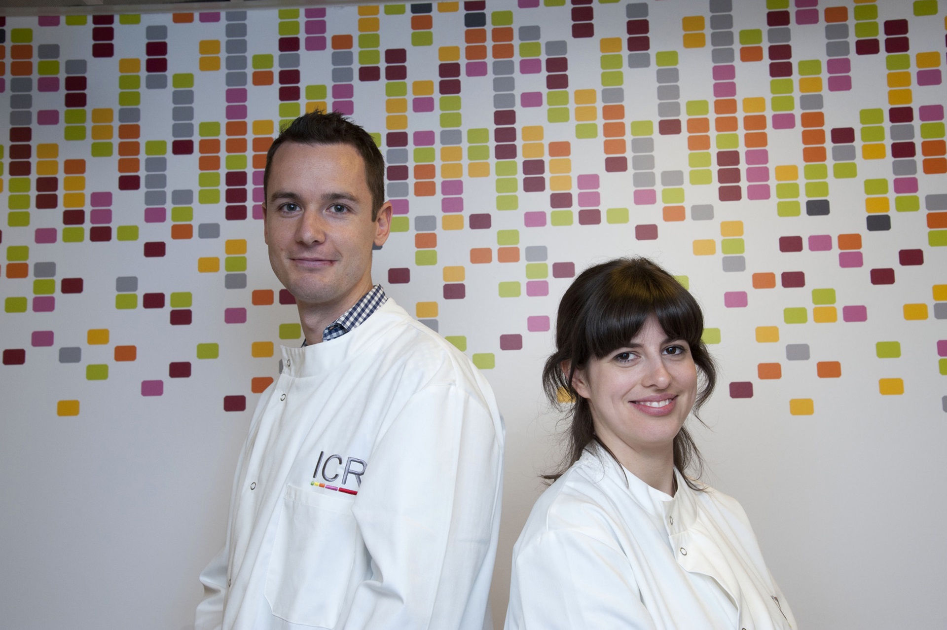 Two scientists standing against a patterned background