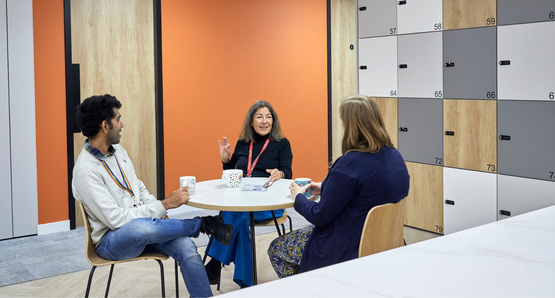 Three people sitting at a table in an office, engaged in discussion and collaboration.