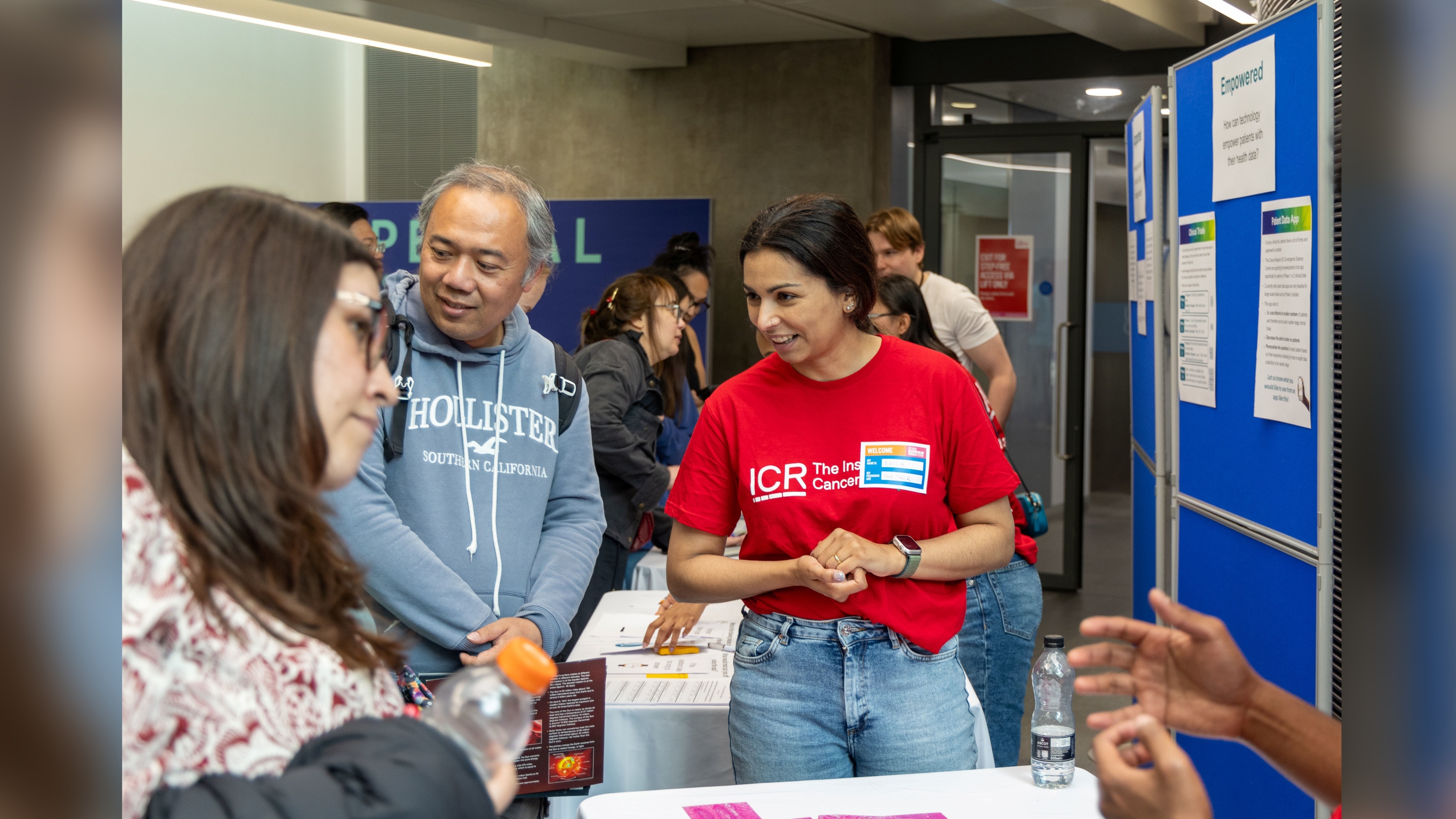 Erica Oliveira 16x9 Erica Oliveira smiling, listening to someone at a public engagement event