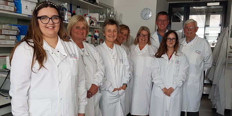 A group of people stand smiling in a Institute of Cancer Research laboratory wearing ICR lab coats