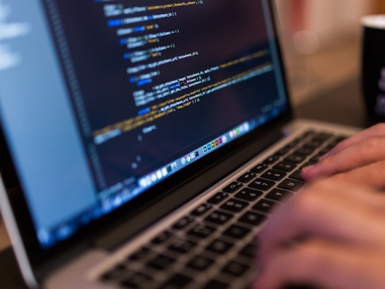 Person typing computer code on laptop computer