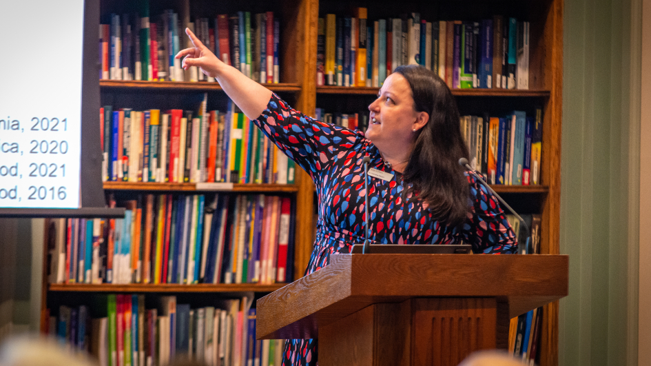 Woman giving a talk and pointing to a screen