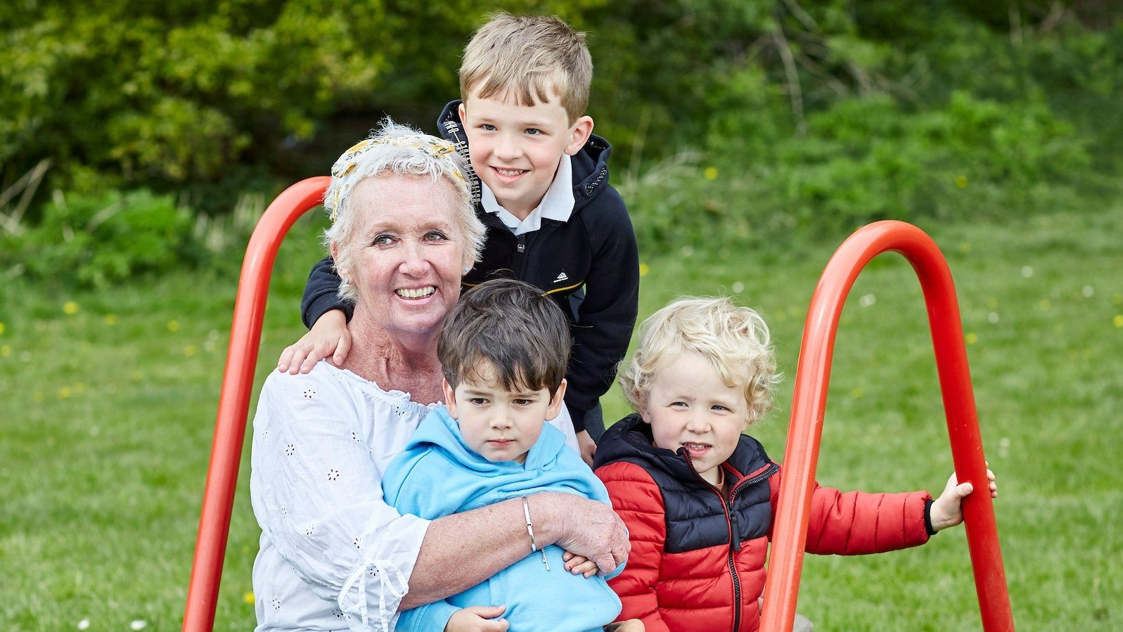 Karen sits outside, surrounded by her three grandsons