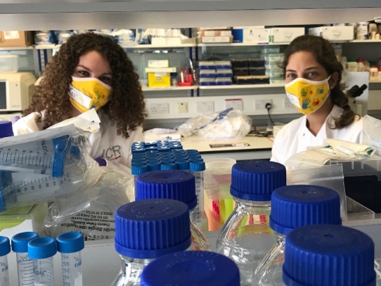 Two female researchers, Olivia and Carolina, wearing facemasks in the lab