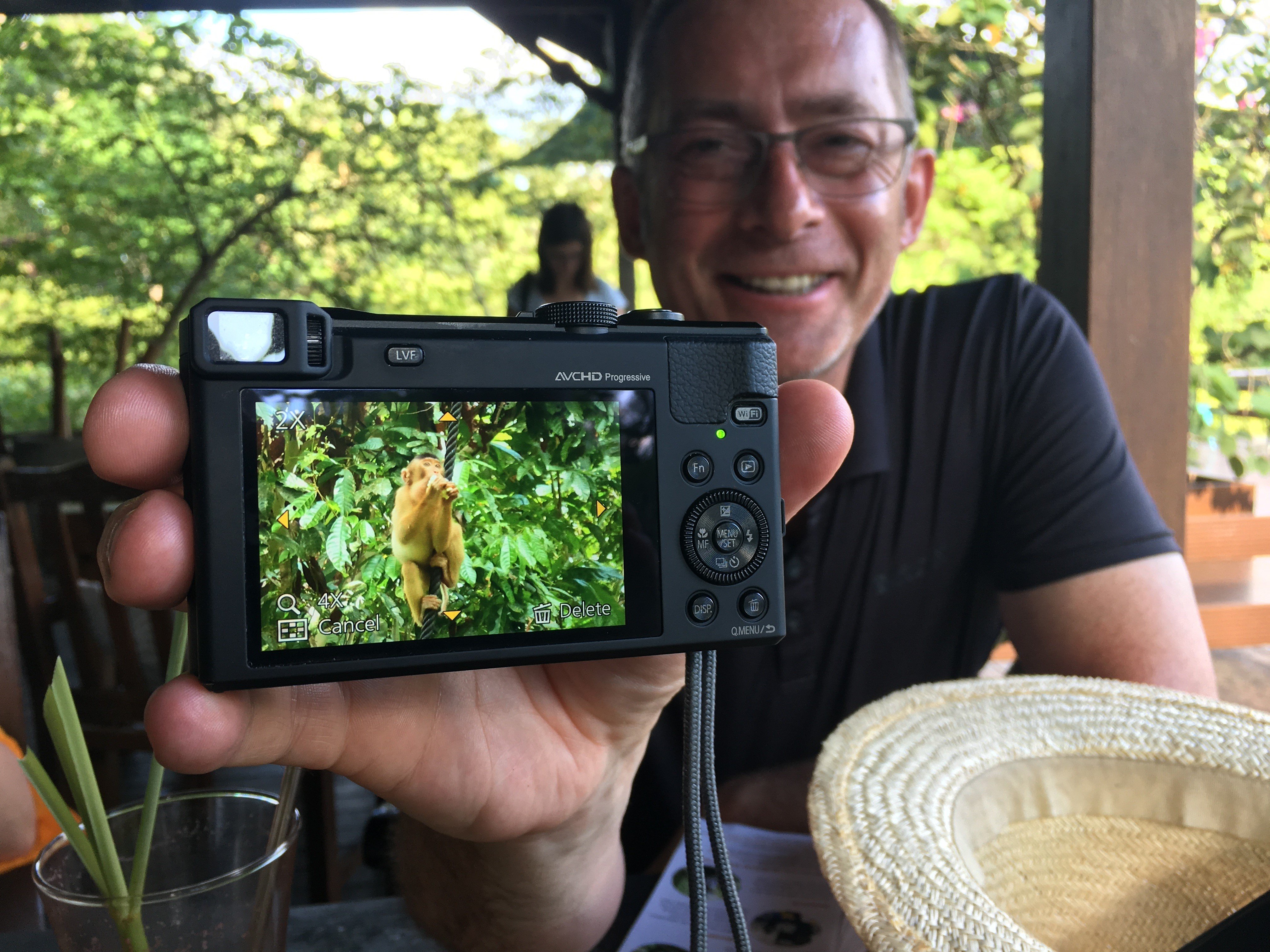 Steve in the background holds a camera showing a monkey