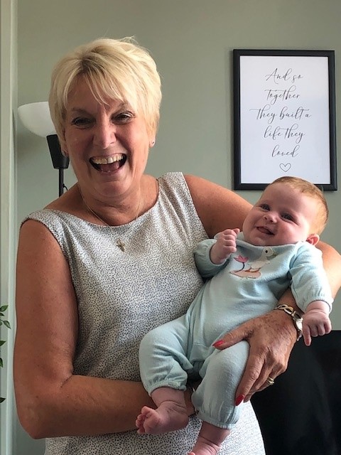 A smiling Sue holding her baby daughter