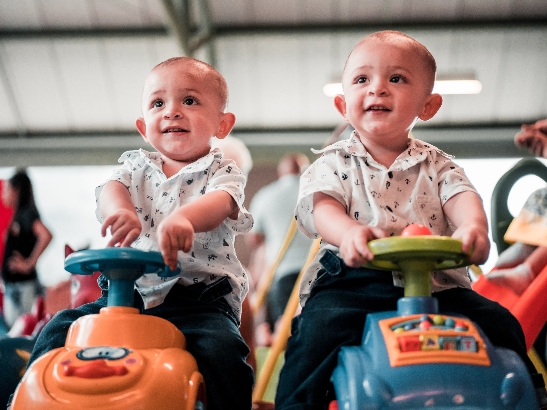 Twins sitting in toy cars