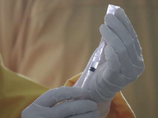 Person filling a syringe with Covid-19 vaccine