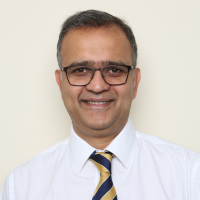 Professor Udai Banjeri wearing a shirt and tie and smiling at the camera