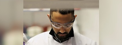 Shakil Khan FBC Shakil Khan wearing a lab coat and protective glasses, looking down